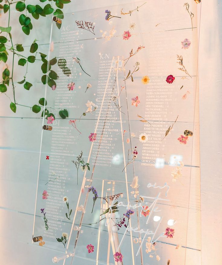 a display case with flowers and plants on it's sides, hanging from the wall