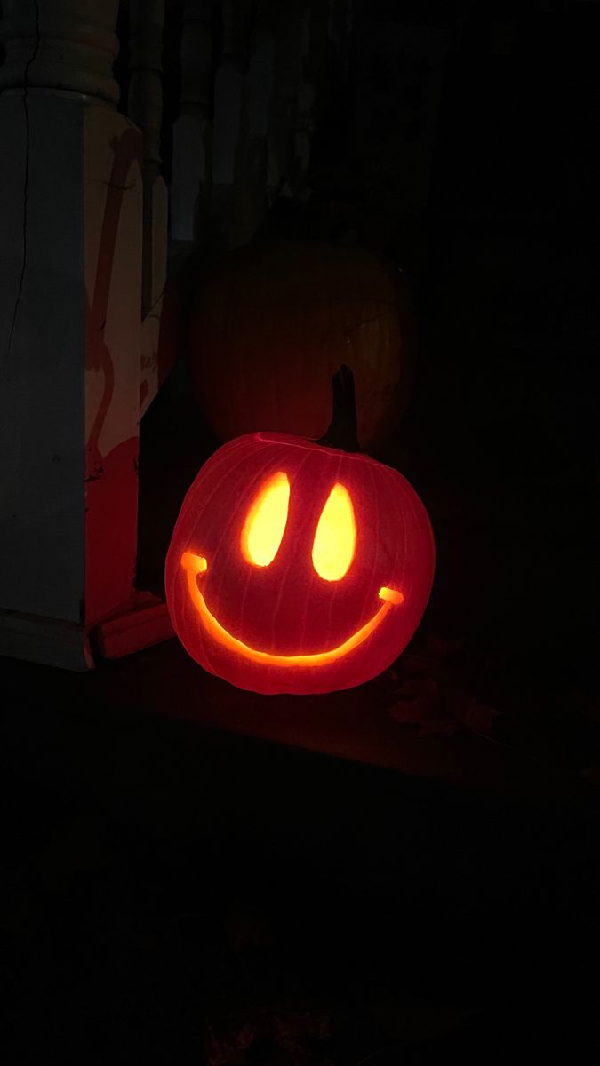 a carved pumpkin with glowing eyes in the dark