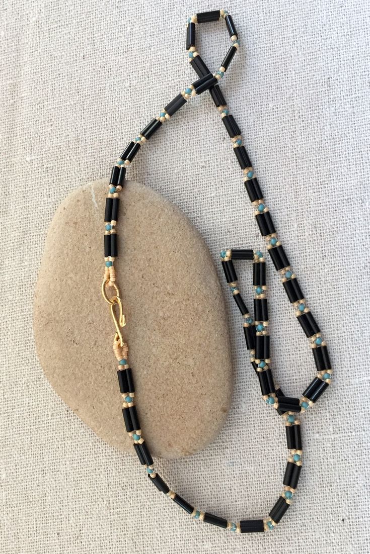 a black and gold beaded necklace on a rock