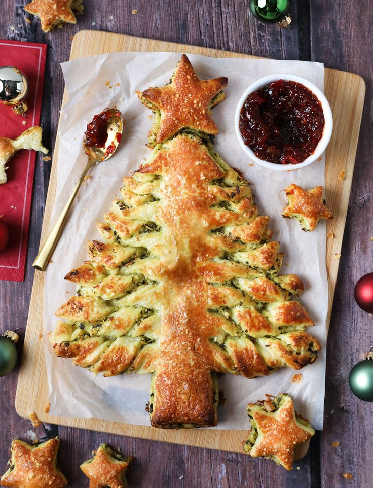 a christmas tree shaped pastry on a cutting board next to other holiday foods and decorations