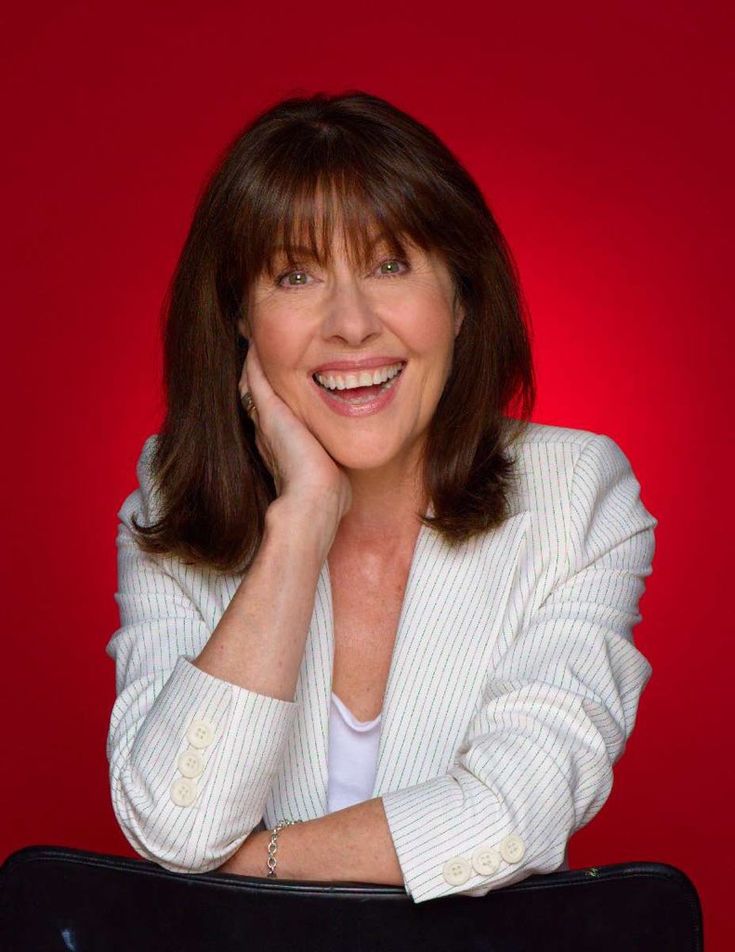 a woman in a white jacket posing for a photo with her hand on her chin