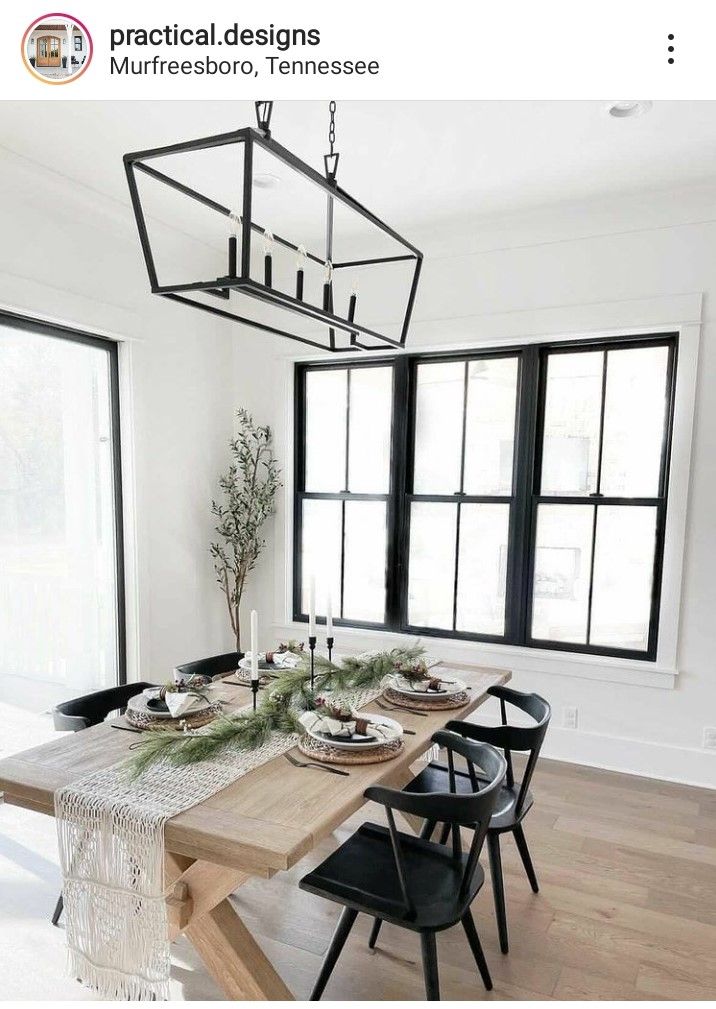 a dining room table with black chairs and a wooden table in front of large windows