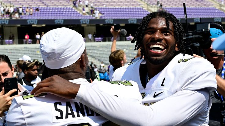 two football players hugging each other in the middle of a stadium with people around them