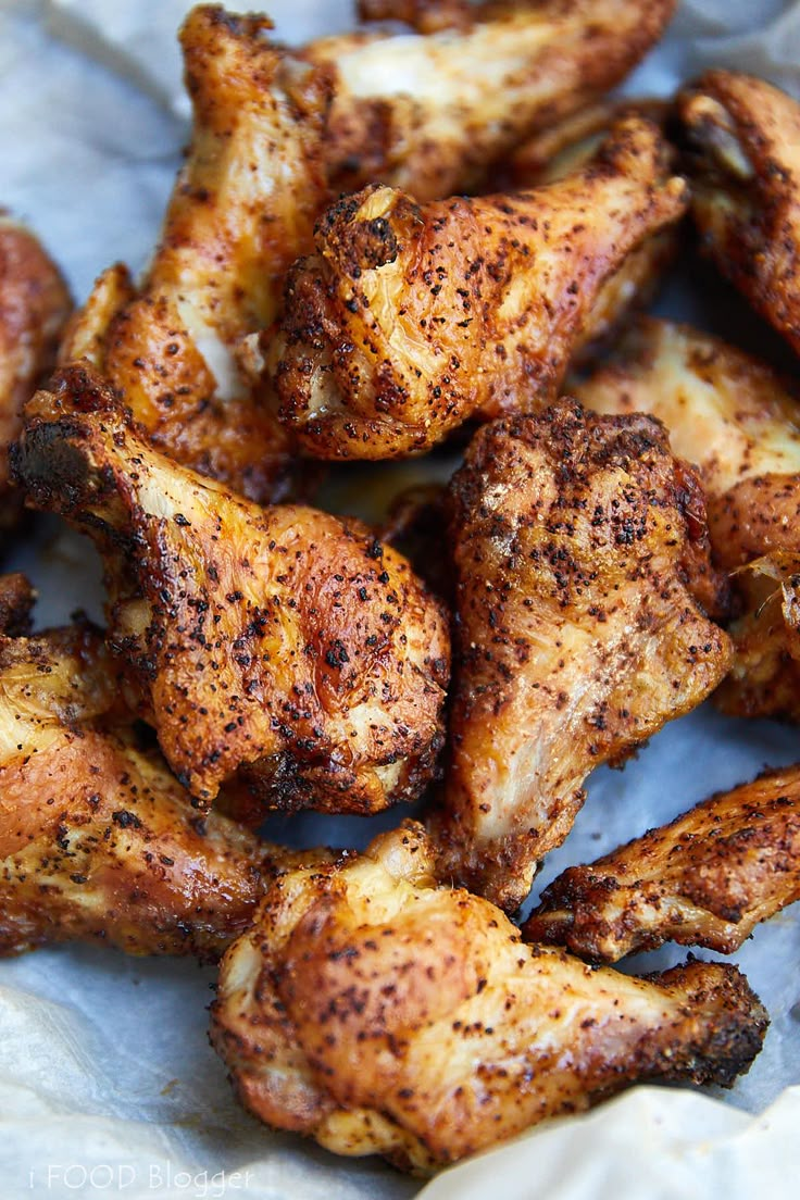 some chicken wings that have been seasoned and are sitting on wax paper