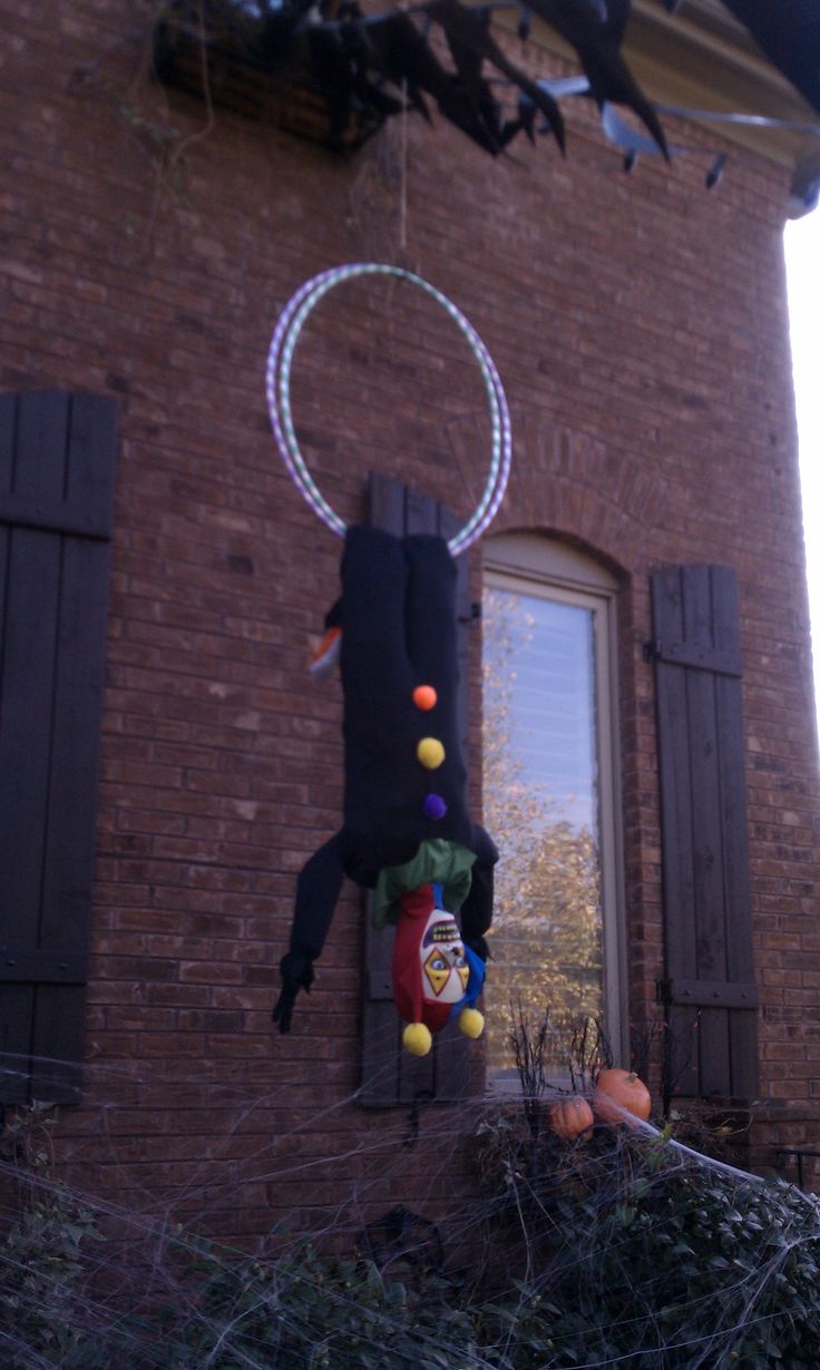 an upside down toy hanging from the side of a brick building in front of a window