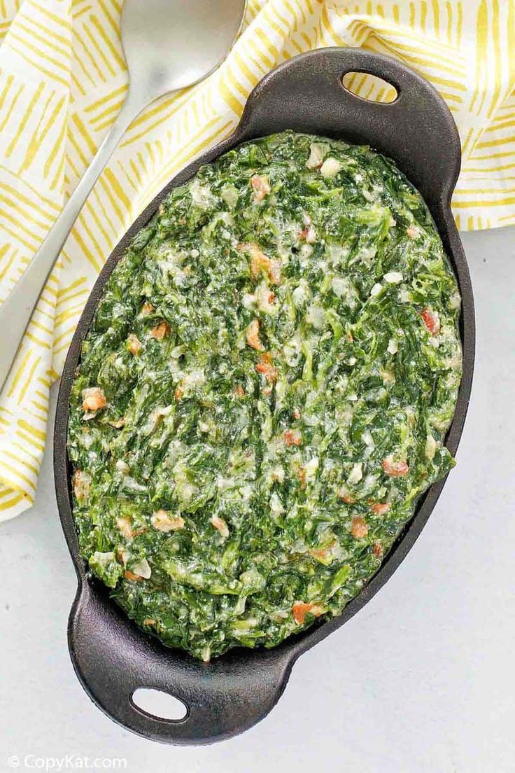 spinach casserole in a cast iron skillet on a yellow and white towel