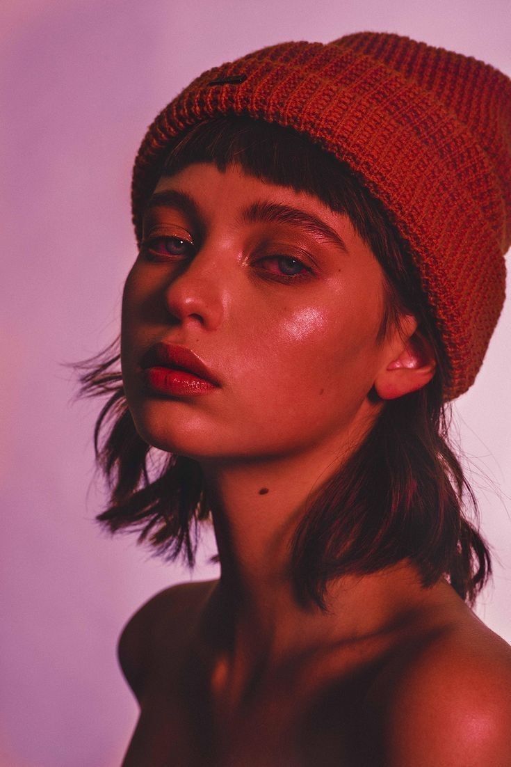 a woman wearing a red knitted hat and looking off to the side with her eyes closed