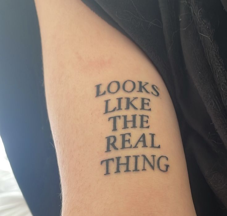 a person with a tattoo that says looks like the real thing on their left arm