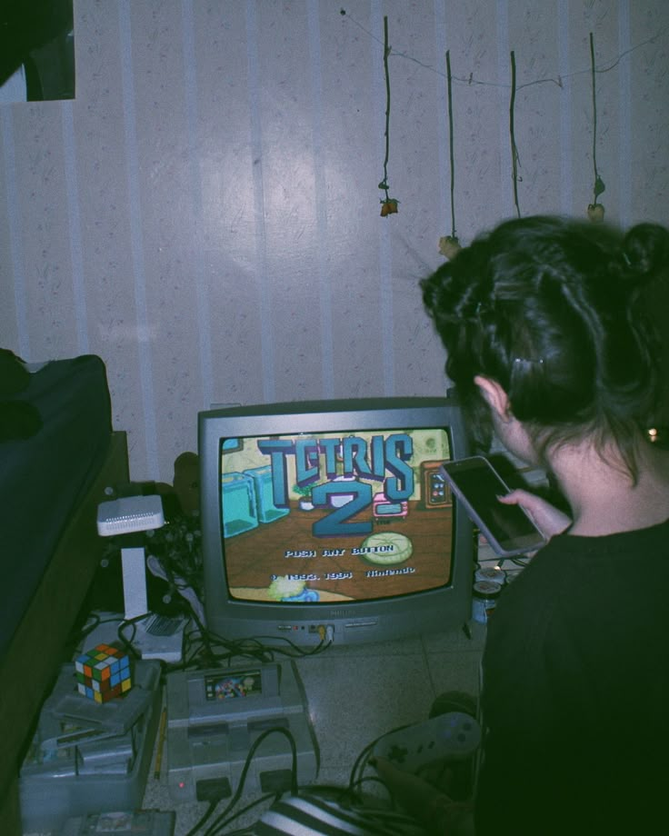 a woman standing in front of a tv holding a cell phone