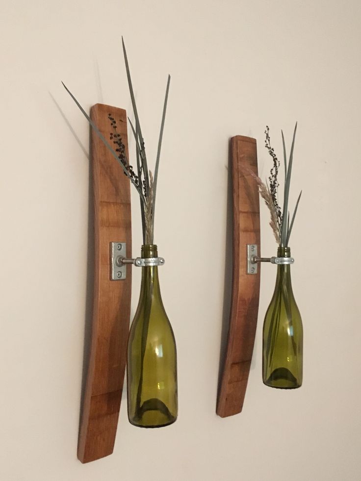 two wine bottles are attached to the wall with plants in them and one is empty