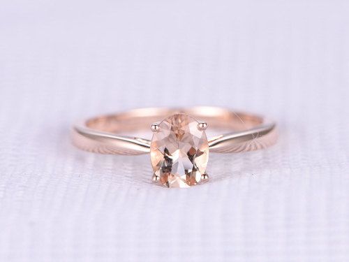 an oval shaped morganite sits on top of a thin band in this engagement ring