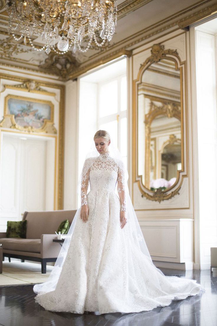 a woman in a white wedding dress standing next to a chandelier