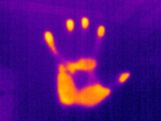 an image of a hand with yellow light in the middle and dark purple background, that appears to be blurry