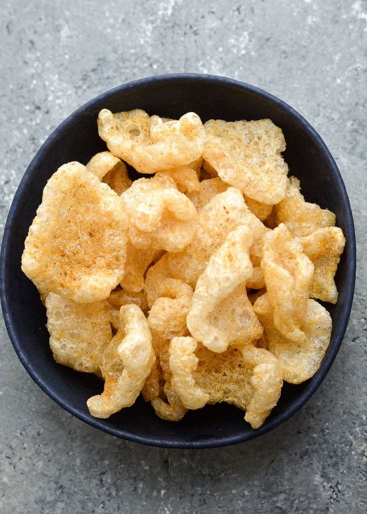 a black bowl filled with fried food on top of a gray counter next to a knife