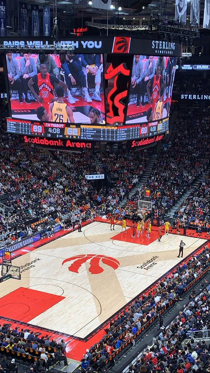 an indoor basketball court with people watching it from the upper level seats in a stadium