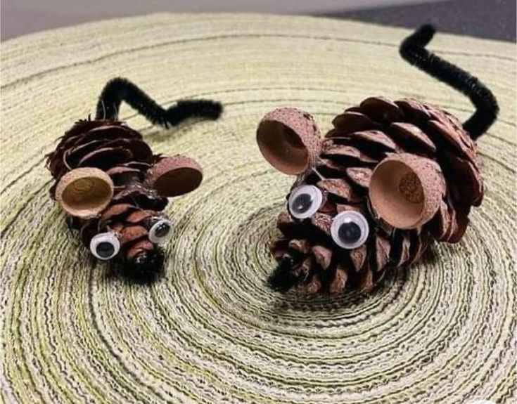 two pine cone mice made to look like they have eyes on their heads and noses