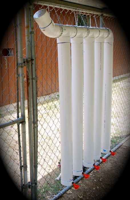 four white pipes attached to a chain link fence