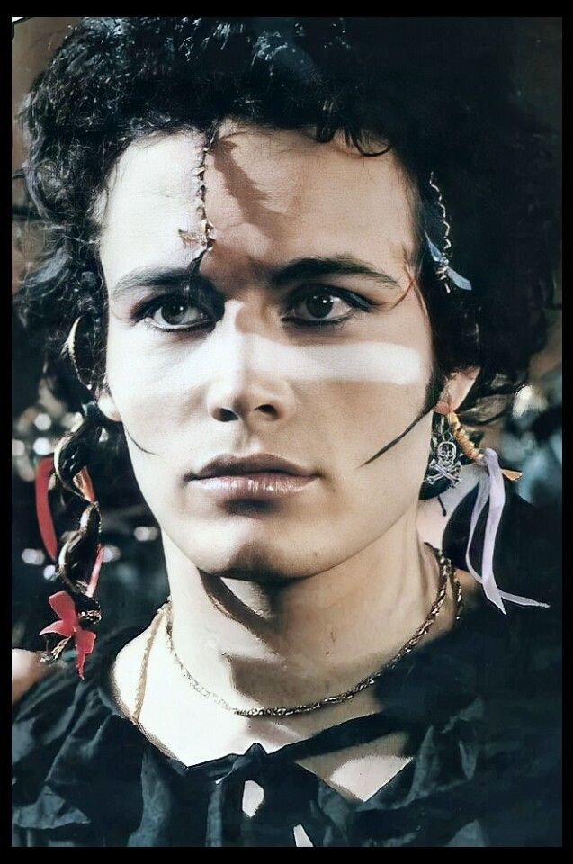 a man with black hair and piercings on his forehead, wearing chains around his neck