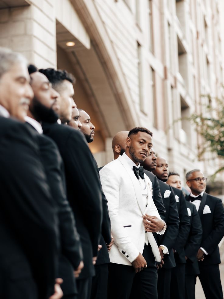 a group of men in tuxedos standing next to each other on the street