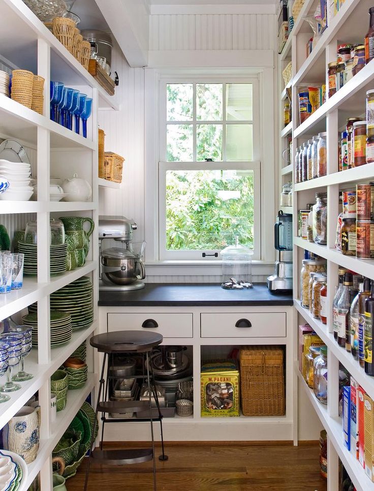 a kitchen filled with lots of shelves next to a window