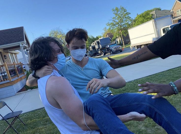 three people sitting on the grass wearing face masks