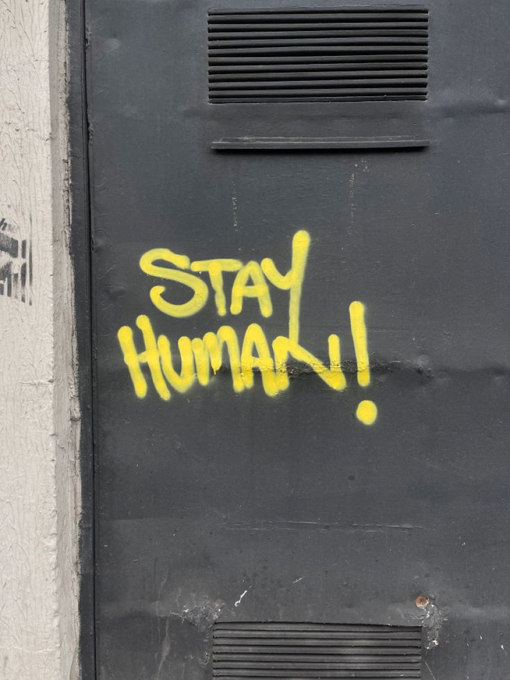 a black door with yellow spray paint that says stay humah on the front and side