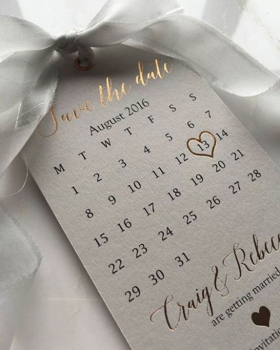 a wedding save the date card tied to a white ribbon with a heart on it