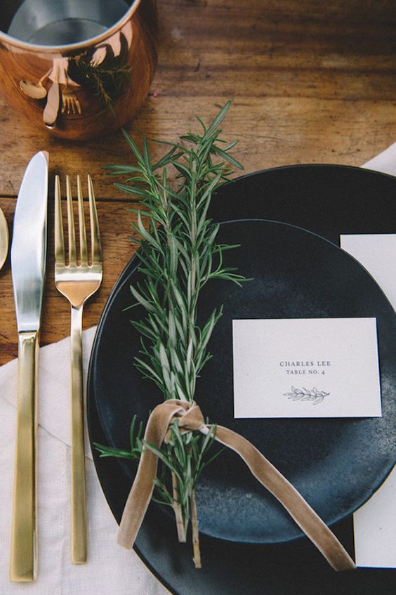 a place setting with silverware, napkins and an empty card on a black plate