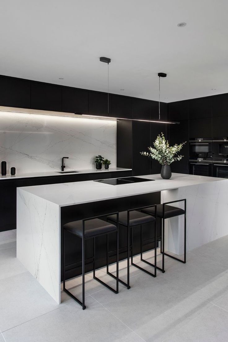 a modern kitchen with black and white cabinets, marble countertops and bar stools