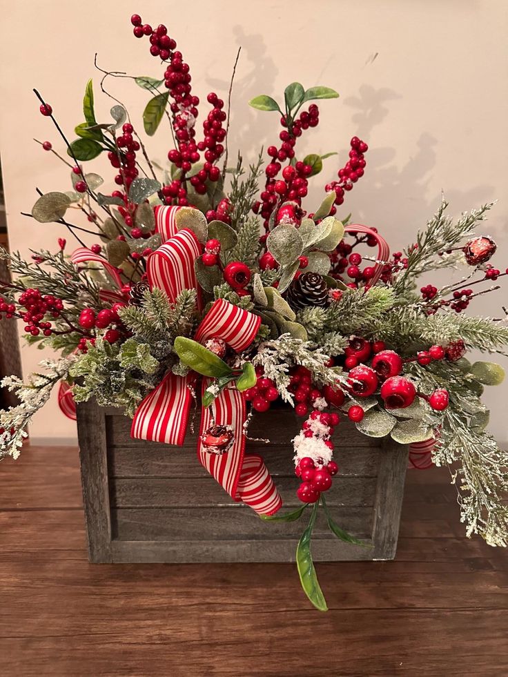 a wooden box filled with red and white flowers on top of a wood table next to a christmas tree