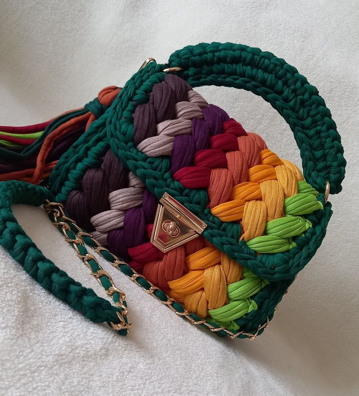 a multicolored handbag is laying on a white surface with a chain around it