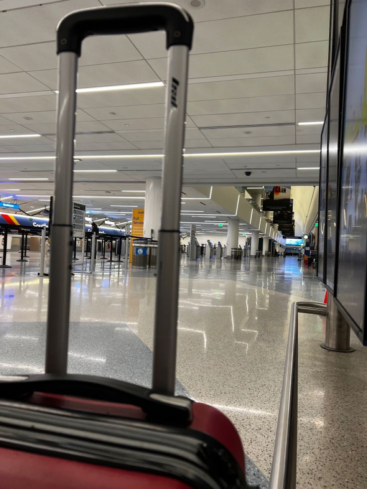 a red piece of luggage sitting in an airport