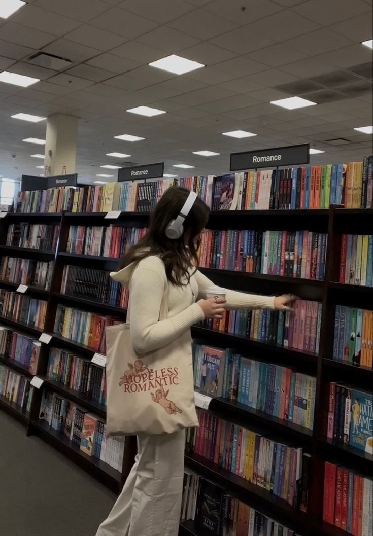 a woman is standing in front of a book shelf with headphones on her ears