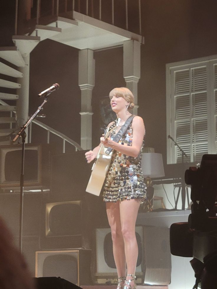 a woman standing on top of a stage holding a microphone and wearing high heeled shoes