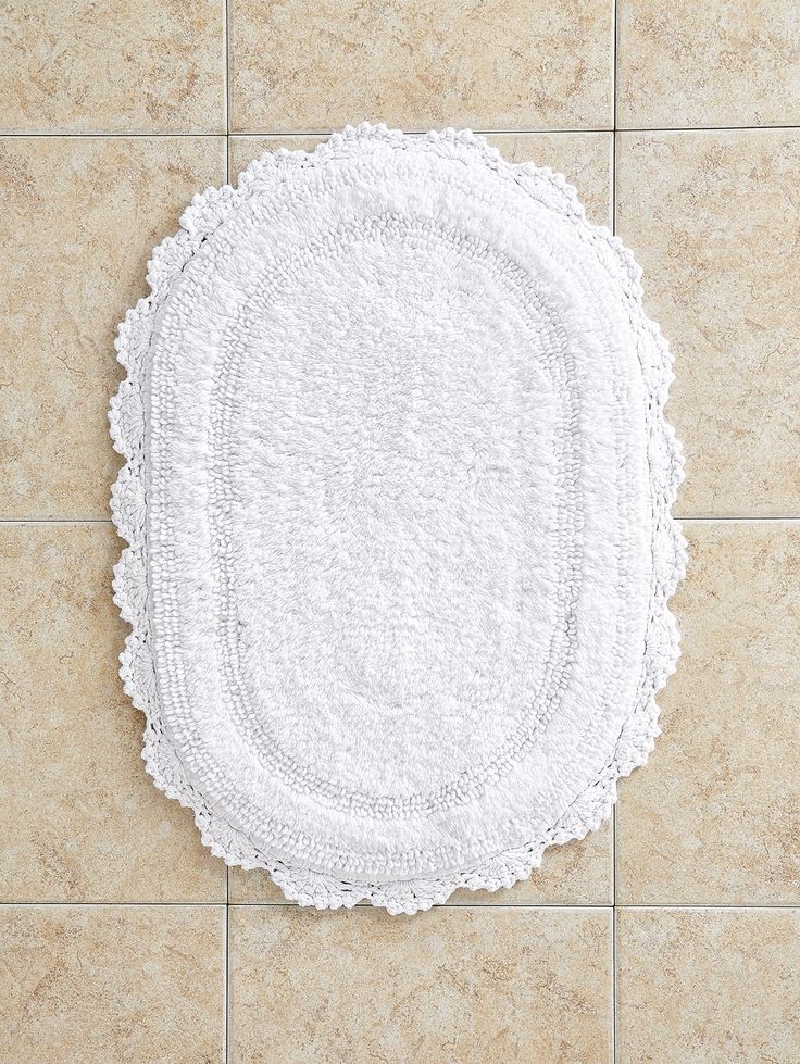 a white rug is on the floor next to a tile wall with a small round doily