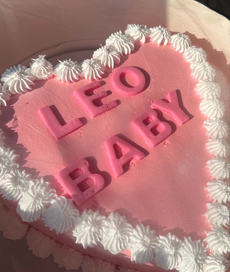 a heart shaped cake with the words leo baby written on it in pink frosting