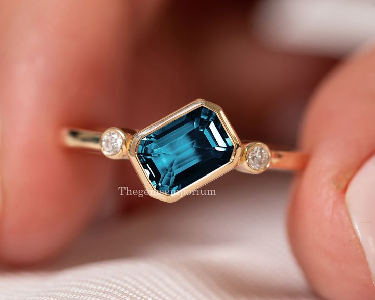 Emerald Cut London Blue Topaz /Topaz Diamond Ring/14k Solid Rose Gold Ring/East West Diamond Ring/November Birthstone/Topaz Engagement Ring  ---------CUSTOM/DUTY-FREE SHIPPING WORLDWIDE, BUYERS DON'T HAVE TO PAY ANY CUSTOM FEES WHILE IMPORTING ------------- Details Made to order Material: 14k/18k gold Color Options: Yellow Gold, White Gold, Rose Gold ★ Center Stone London Blue Topaz, Emerald-cut Size: 5x7mm Approx. Weight (Ct): 0.98 ★ Accent Stones Diamond Round Size: 1.8 mm * 2 Nos. Approx. Weight (Ct): 0.05 ★ 100% Natural Diamond and Gemstones ★ Diamond: Round Brilliant cut, G-H Color, SI Clarity ☂ Shipped with Insured Shipping with 4-7 business days. ➦ 100% Free Returns. ➦ Our Jewelry comes with Lifetime Warranty. (Stone Replacement not included) ✈ We offer free EXPRESS shipping across Luxury Modern Topaz Wedding Ring, Rectangle Topaz Ring, Luxury Blue Topaz Emerald Cut Jewelry, Luxury Modern Topaz Ring With Round Shape, Luxury Emerald Cut Topaz Ring With Diamond Accents, London Blue Topaz Ring Yellow Gold, Blue Topaz Engagement Rings, Yellow Topaz Ring, London Blue Topaz Engagement Ring