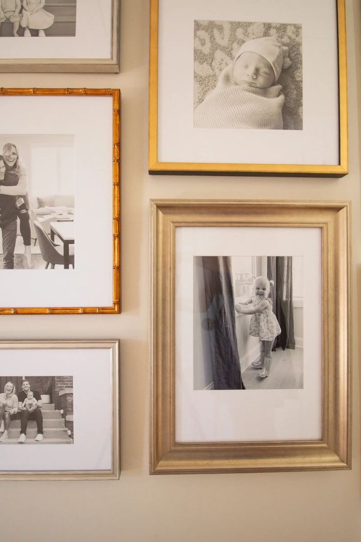 several framed pictures hang on the wall above a baby's crib