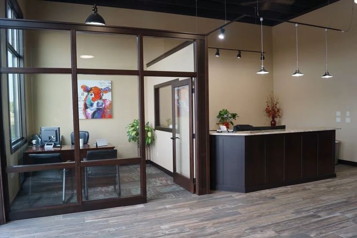 an office with wood floors and glass doors leading to the front desk, sitting on top of a hard wood floor