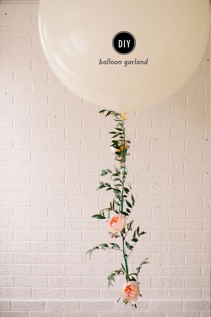 a white balloon with flowers hanging from it's side in front of a brick wall