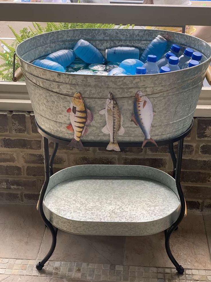 a large metal bucket filled with water and fish on top of a table next to a window