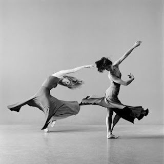 two women are dancing in the middle of a dance studio, one is holding her leg up