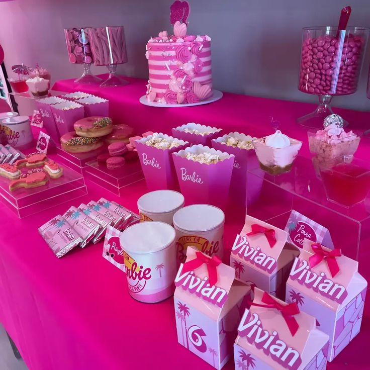 a pink table topped with lots of desserts and candy bar items on top of it