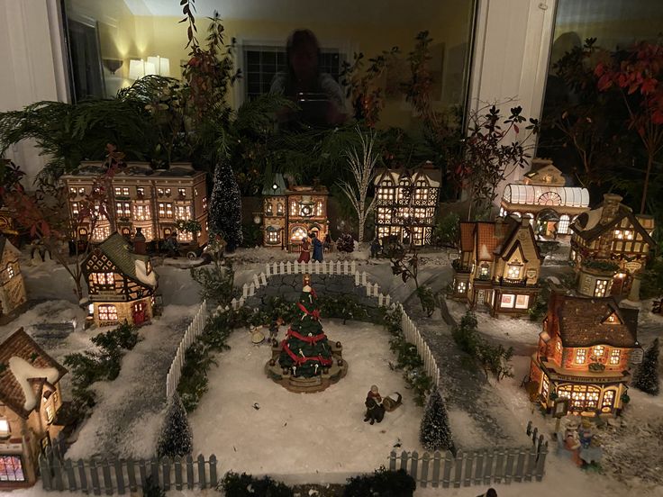 a christmas village with lit up houses and trees in the snow, surrounded by candles