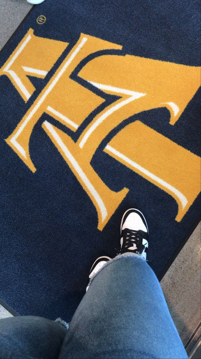 a person sitting on the floor with their feet up next to a yellow and blue rug