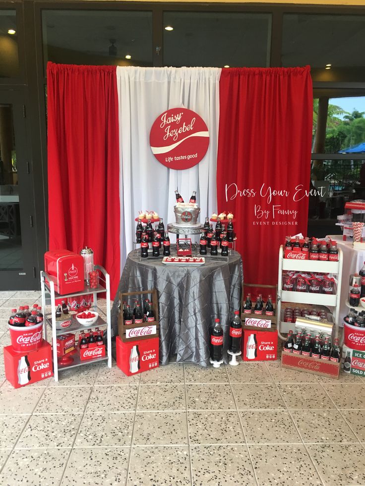 a table topped with lots of red and white bottles next to a sign that says coca - cola