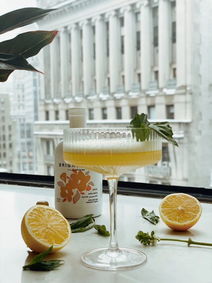 a glass filled with liquid sitting on top of a table next to lemons and leaves