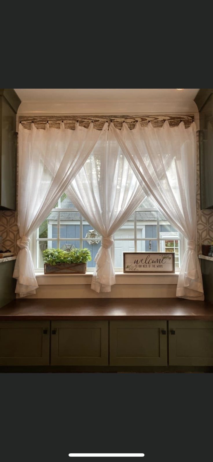 a kitchen window with curtains and plants in the potted planter on the windowsill