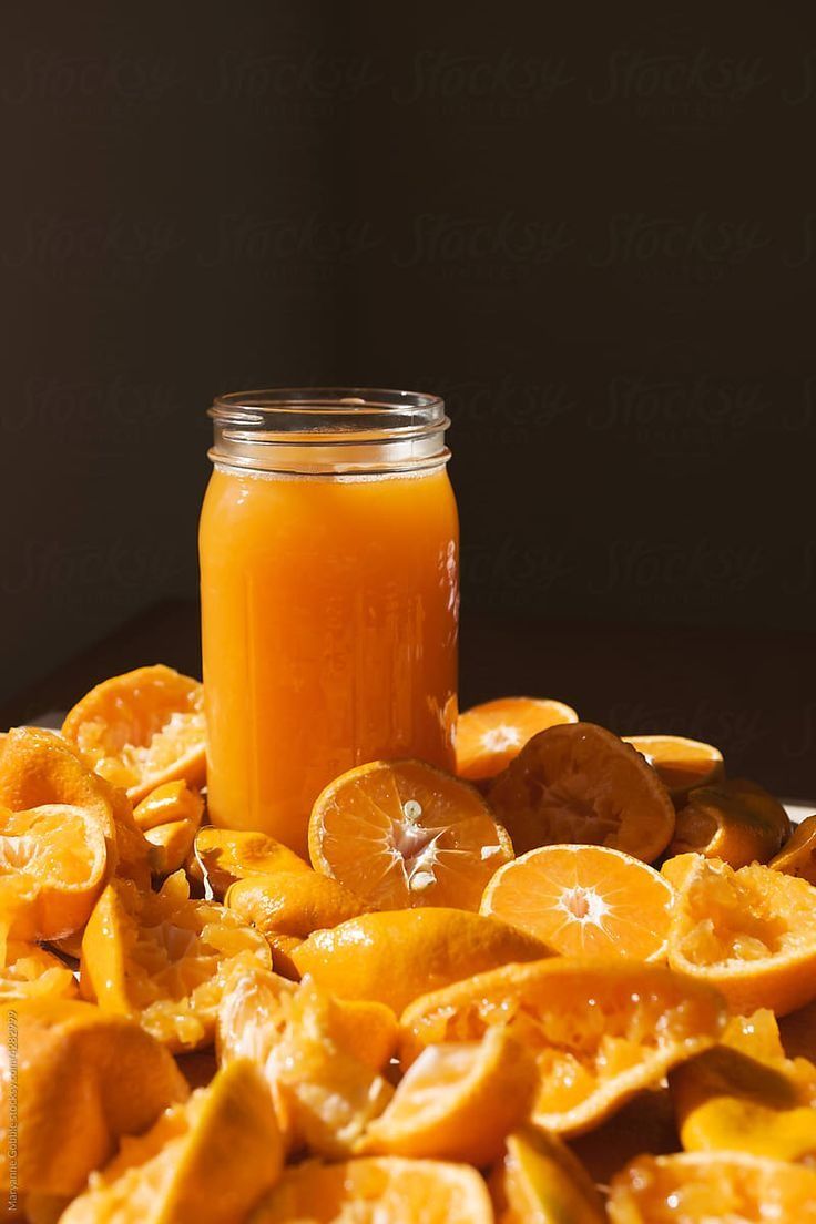 a jar filled with orange slices next to a pile of sliced oranges