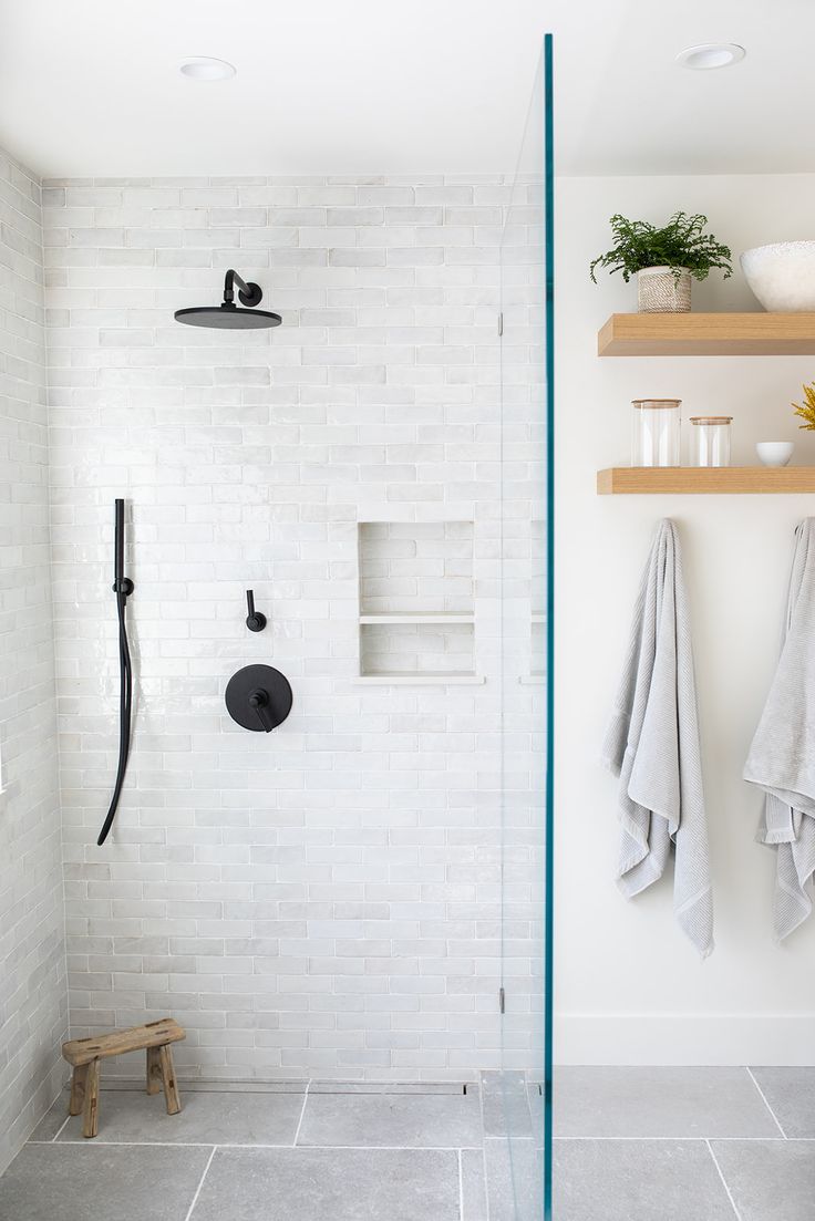 a white tiled bathroom with shelves and towels